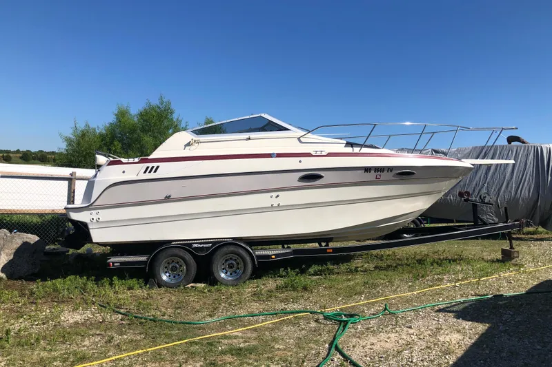 Slide: The Image of 1992 Maxum 2300 SC boat on trailer, parked outdoors under clear blue sky. - 13