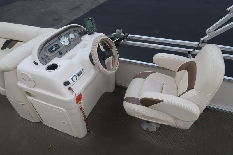 Slide: The Image of 2010 Smoker Craft Sunchaser 8522 boat helm with beige captain's chair and dashboard controls. - 24