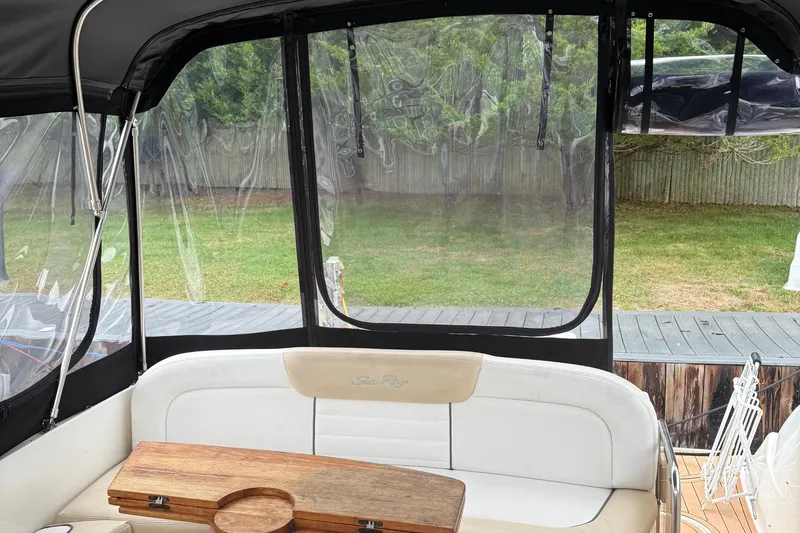 Slide: The Image of 2008 Sea Ray 330 Sundancer cockpit with seating and wooden table, enclosed by clear panels. - 25