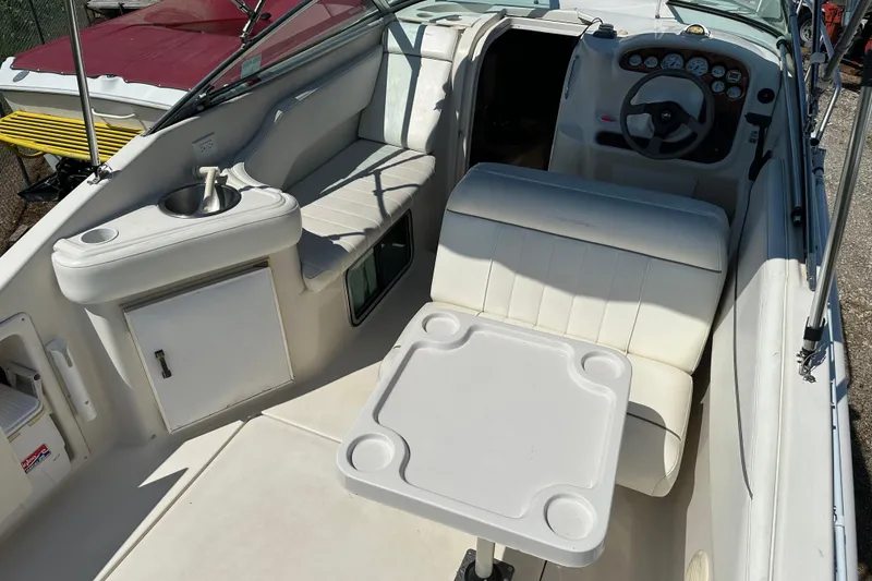 Slide: The Image of 1999 Monterey 262 Cruiser interior with seating, table, and helm, showcasing white upholstery. - 3
