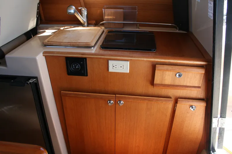 Slide: The Image of Compact kitchen area in a 2018 Ranger Tugs R-23 boat with wooden cabinetry. - 10