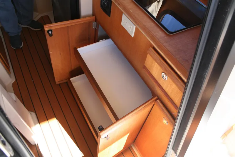 Slide: The Image of 2018 Ranger Tugs R-23 interior with open wooden cabinets and drawers. - 11