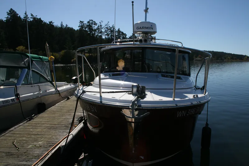 Slide: The Image of 2018 Ranger Tugs R-23 boat docked on a calm lake with trees in the background. - 3