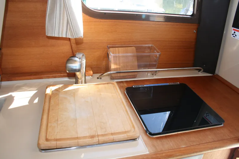 Slide: The Image of 2018 Ranger Tugs R-23 kitchen area with sink, cutting board, and stove. - 8