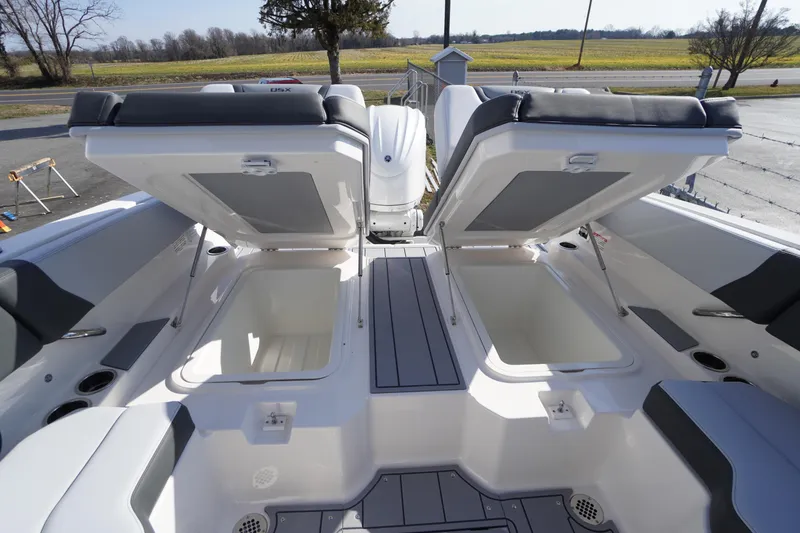 Slide: The Image of 2026 Chaparral 250 OSX boat with open storage compartments and cushioned seating. - 34