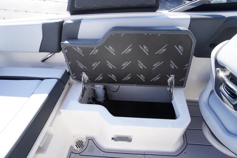 Slide: The Image of 2026 Chaparral 250 OSX boat storage compartment with open lid, showcasing interior space. - 41