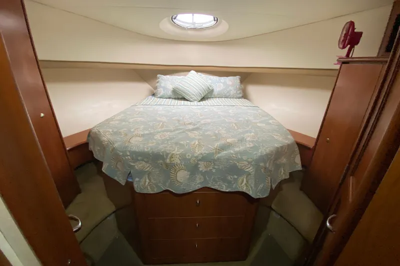 Slide: The Image of 2007 Silverton 36 Convertible cabin with bed, wooden cabinets, and porthole window. - 35