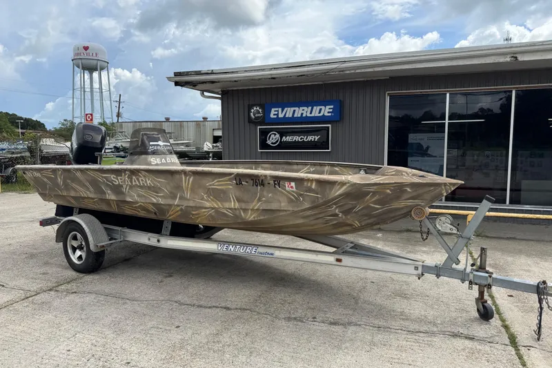 Slide: The Image of 2011 SeaArk XV180 CC boat on trailer, parked outside a dealership under cloudy skies. - 13