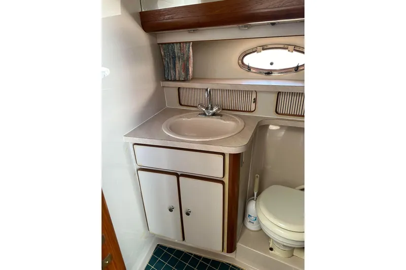 Slide: The Image of 1992 Regal Commodore 400 boat bathroom with sink, cabinet, and porthole window. - 31