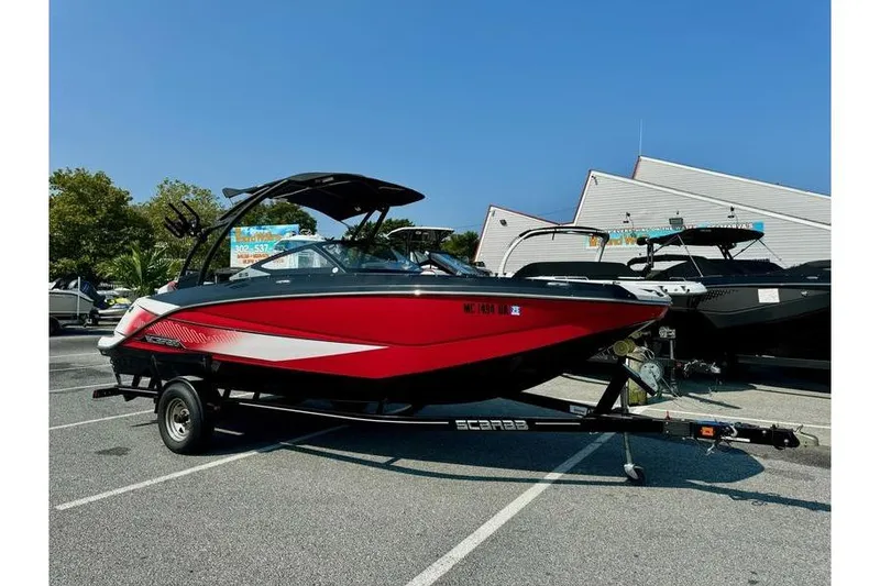 The Image of 2015 Scarab 215 HO Impulse boat in vibrant red on a trailer, parked outdoors. - 0