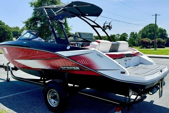 Slide: The Image of 2015 Scarab 215 HO Impulse boat on trailer, red and white design, parked outdoors. - 1
