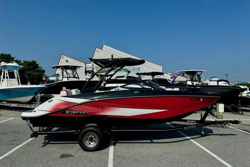 Slide: The Image of 2015 Scarab 215 HO Impulse boat in a parking lot, vibrant red and white design. - 2