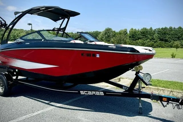 Slide: The Image of 2015 Scarab 215 HO Impulse boat in a parking lot, red and black design, on a trailer. - 3