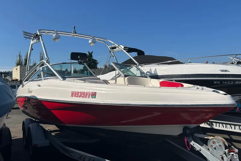 Slide: The Image of 2004 Rinker 212 Captiva Bowrider boat with red and white exterior on trailer. - 1