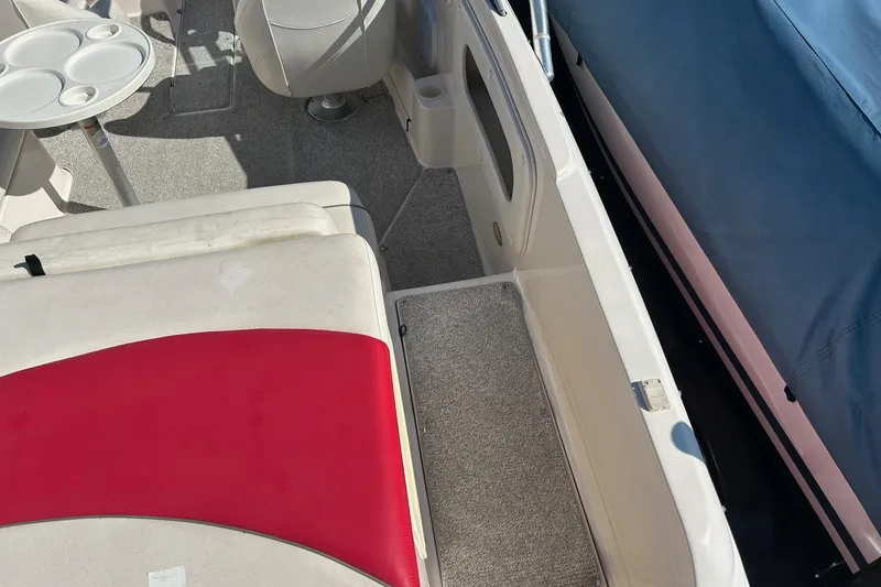 Slide: The Image of 2004 Rinker 212 Captiva Bowrider interior with red and white seating, table, and carpeted floor. - 16