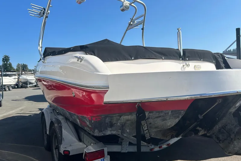 Slide: The Image of 2004 Rinker 212 Captiva Bowrider on trailer, red and white hull, covered, sunny day. - 19