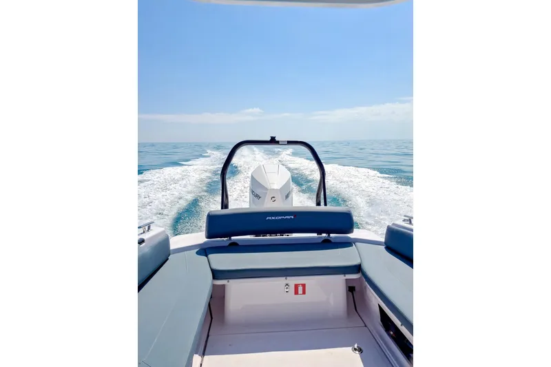 Slide: The Image of 2024 Axopar 25 Cross Top boat cruising on open water, rear view. - 3