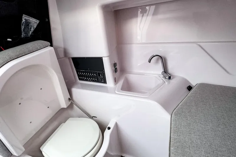 Slide: The Image of 2024 Axopar 25 Cross Top interior with compact toilet, sink, and control panel. - 9