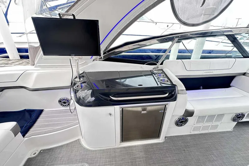 Slide: The Image of 2022 Formula 350 Crossover Bowrider I/O interior with TV, seating, and mini-fridge. - 6