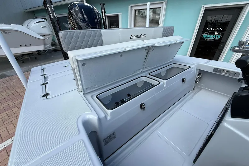 Slide: The Image of 2026 Action Craft 20 Flatsmaster boat with open storage compartments, displayed at a sales location. - 10