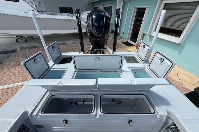 Slide: The Image of 2026 Action Craft 20 Flatsmaster boat with open storage compartments and motor, docked near a building. - 14