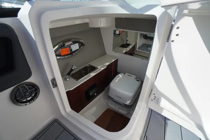 Slide: The Image of 2026 Chaparral 250 OSX boat interior with sink, mirror, and portable toilet. - 24