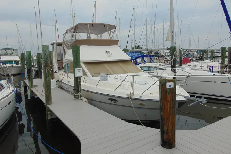 Slide: The Image of 1999 Maxum 4100 SCA yacht docked at marina with sailboats in background. - 0