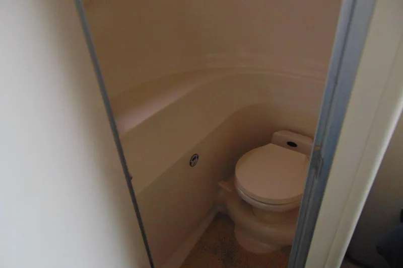Slide: The Image of Compact bathroom in 1999 Maxum 4100 SCA boat, featuring a toilet and enclosed space. - 10