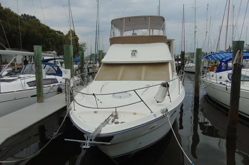 Slide: The Image of 1999 Maxum 4100 SCA yacht docked at marina, surrounded by sailboats. - 2