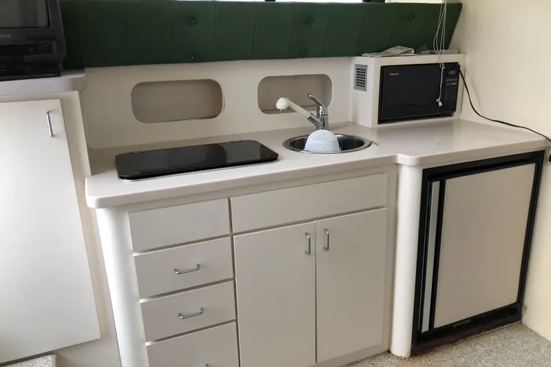 Slide: The Image of 1994 Mainship 31 Sedan Bridge kitchen with sink, microwave, and compact fridge. - 11