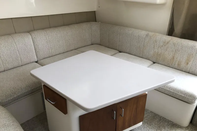 Slide: The Image of 1994 Mainship 31 Sedan Bridge interior with cushioned seating and white table. - 15