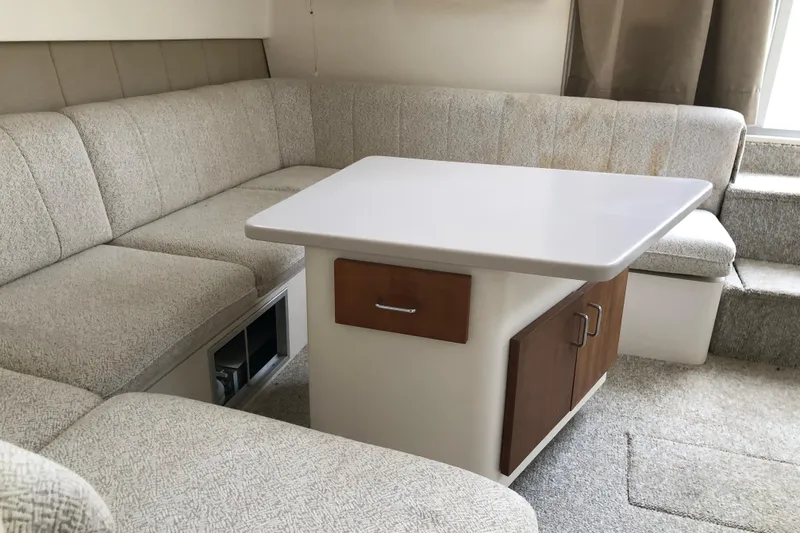 Slide: The Image of 1994 Mainship 31 Sedan Bridge interior with beige seating and a central table. - 17
