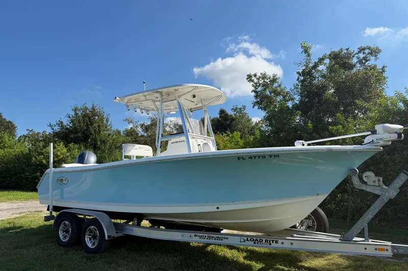 The Image of 2017 Sea Hunt Ultra 234 boat on trailer, surrounded by greenery and blue sky. - 5