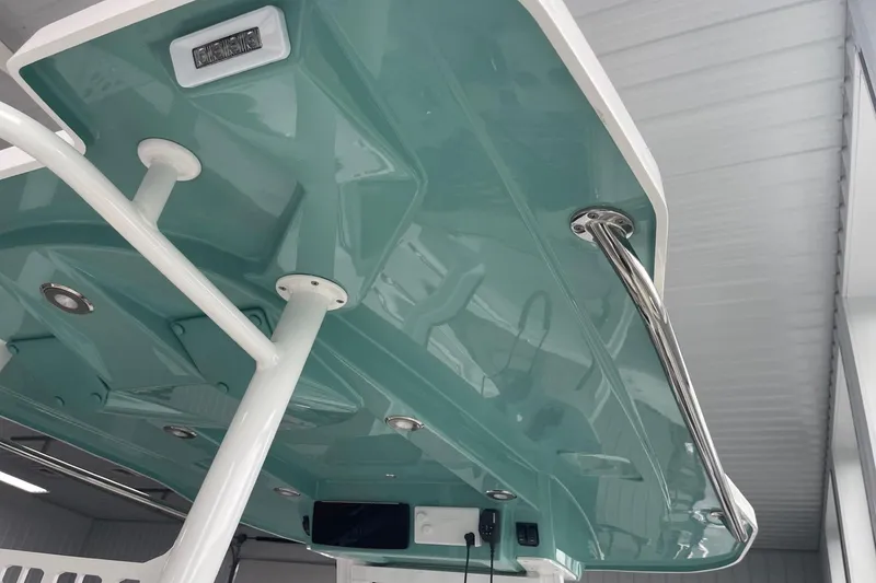 Slide: The Image of 2026 Hurricane Center Console 24 OB boat, teal underside, stainless steel rail, indoor setting. - 35