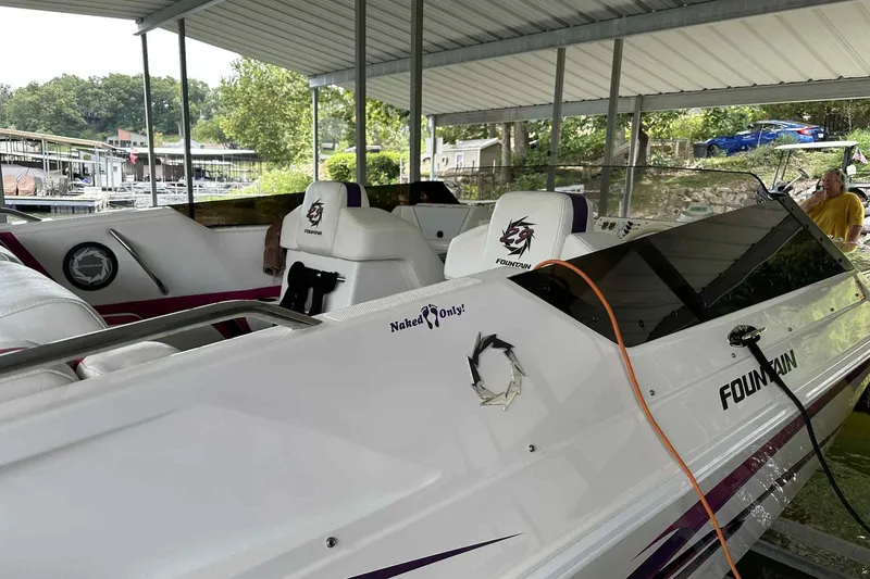 Slide: The Image of 1997 Fountain 29 Fever speedboat docked under a covered marina, featuring sleek white and purple design. - 19