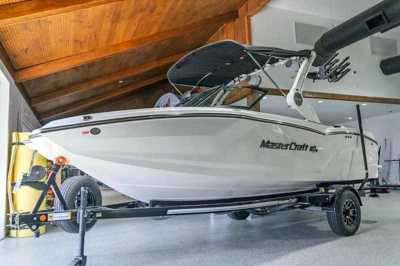 The Image of 2026 MasterCraft NXT20 boat on trailer in a modern garage setting. - 0