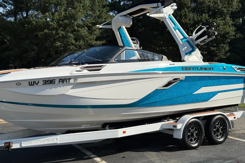 Slide: The Image of 2023 Centurion Ri230 boat with blue accents on a trailer, parked outdoors. - 12