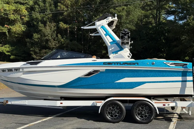 Slide: The Image of 2023 Centurion Ri230 boat on trailer, blue and white design, parked outdoors. - 13
