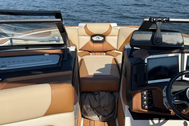 Slide: The Image of 2023 Centurion Ri230 boat interior with tan and brown seating, dashboard, and steering wheel. - 15
