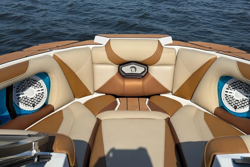 Slide: The Image of 2023 Centurion Ri230 boat interior with tan and brown seating, surrounded by water. - 18