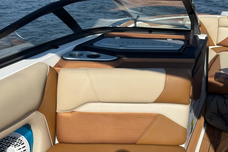 Slide: The Image of 2023 Centurion Ri230 boat interior with tan and cream seating, cup holders, and dashboard. - 26