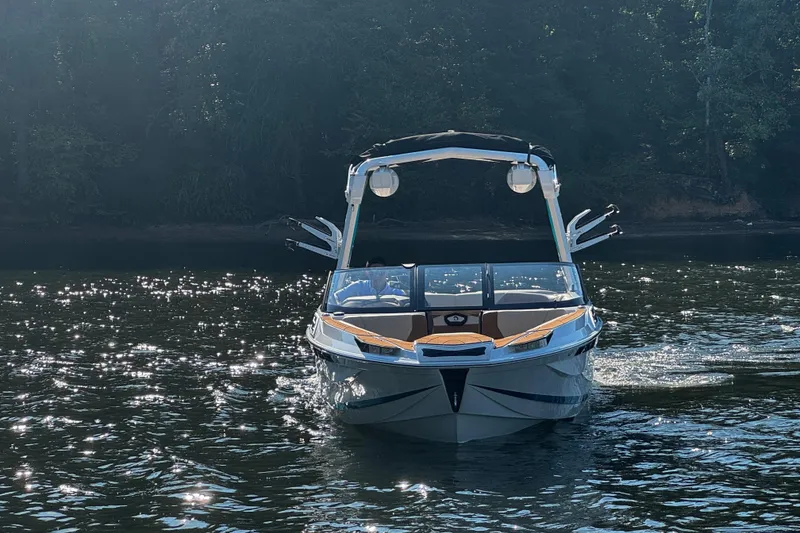Slide: The Image of 2023 Centurion Ri230 boat on shimmering water, surrounded by trees. - 5