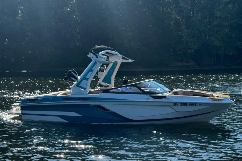 Slide: The Image of 2023 Centurion Ri230 boat on a sunlit lake with forest background. - 9