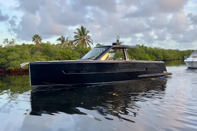 Slide: The Image of 2016 Fjord 48 Open yacht on calm water, surrounded by lush greenery and palm trees. - 2