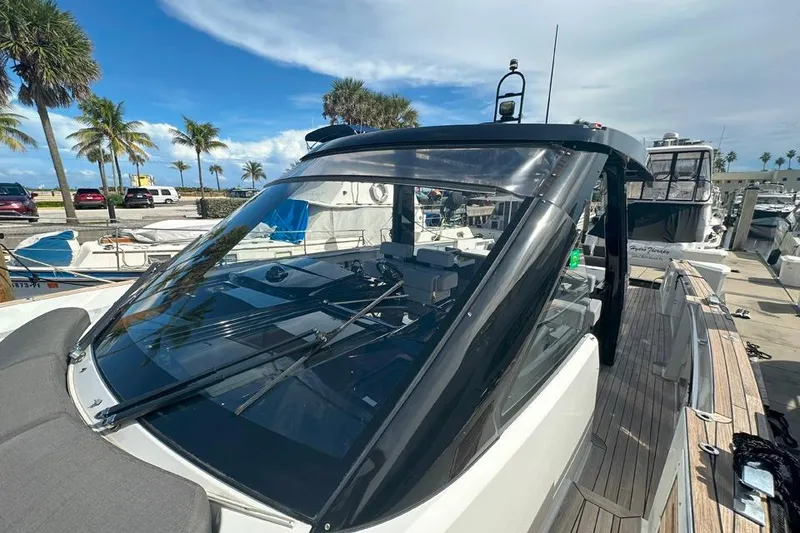 Slide: The Image of 2016 Fjord 48 Open yacht docked at a marina with palm trees and blue sky. - 48
