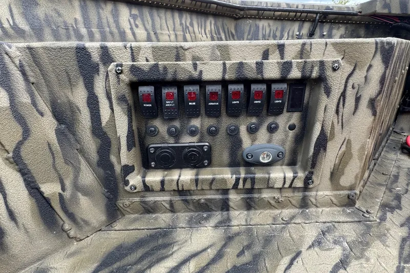 Slide: The Image of Control panel of 2025 SeaArk 1752 Slayer Pro boat with camouflage design and switches. - 9