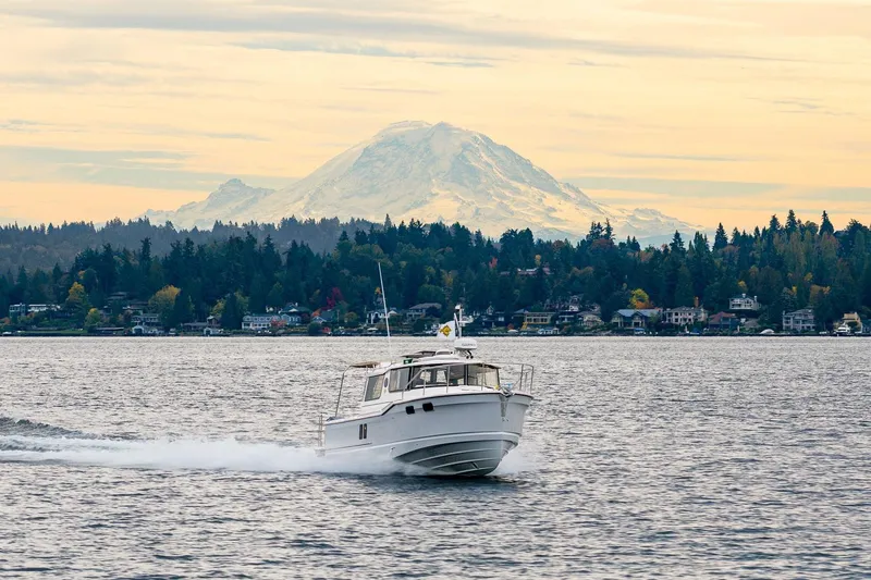 Slide: The Image of 2026 Ranger Tugs R-27 cruising on a scenic lake with mountain backdrop. - 34