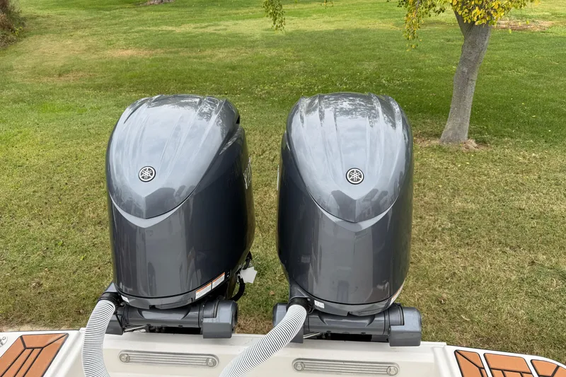 Slide: The Image of 2026 Ranger Tugs R-27 boat on trailer, towed by a truck, surrounded by trees. - 4