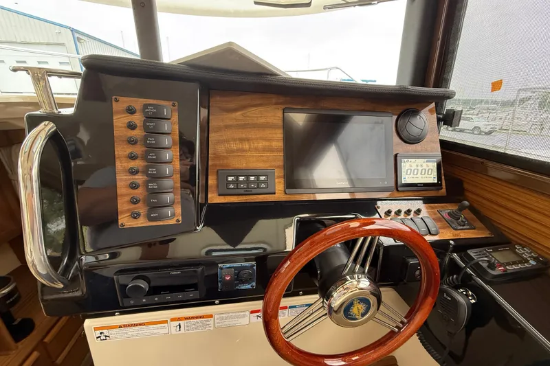 Slide: The Image of 2026 Ranger Tugs R-27 boat interior at a marina, showcasing seating and docked sailboats. - 8