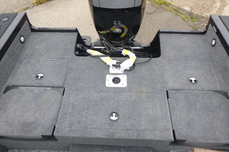 Slide: The Image of 2026 Tracker Targa V-18 Combo boat deck with motor, featuring gray carpeting and storage compartments. - 13